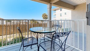 A covered outdoor area with a round glass table and four metal chairs. - Bayview condo only steps from the beach w/ shared pool and peaceful location (Navarre Beach)