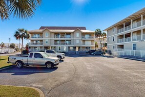 A multi-story hotel with a flat roof and balconies, parking in front.