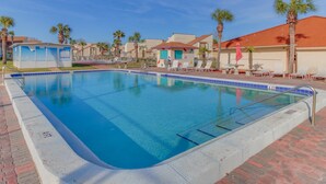 A swimming pool with a clear blue water, surrounded by palm trees and lounge chairs. - Cozy condo with pools, tennis, gym, mini golf, beach access, & balcony (Panama City Beach)