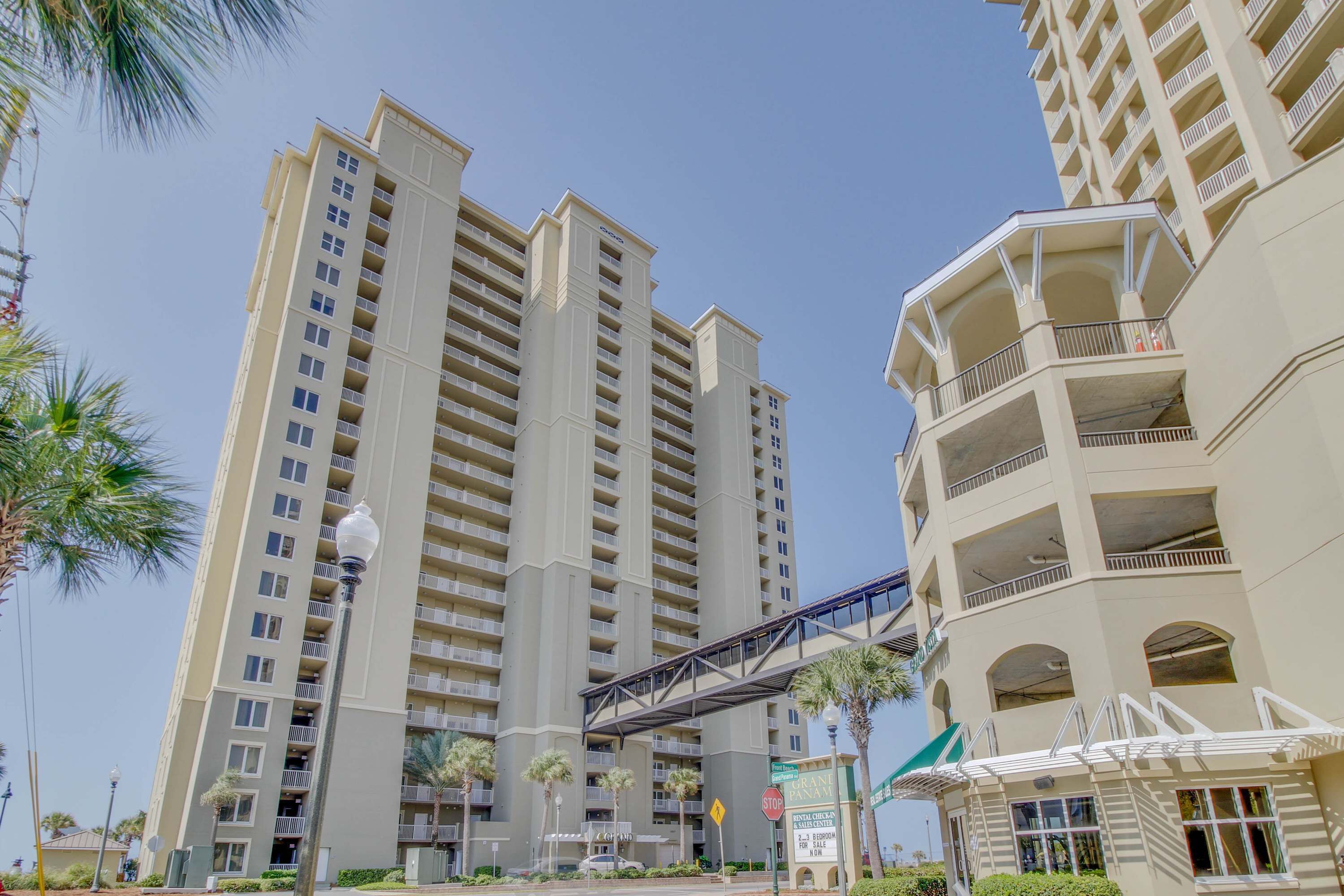 A high-rise building with multiple balconies and a pedestrian bridge.