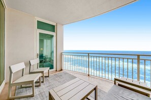 Un balcó amb vista a l'oceà, una porta que dona a una habitació i dues cadires blanques.