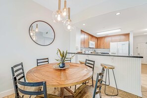 A modern kitchen with wooden cabinets, a white countertop, and a central island. - Renovated oceanfront condo with pools, hot tub & AC (Panama City Beach)