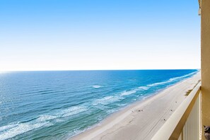 Une vue sur la plage depuis un balcon, avec un ciel dégagé.