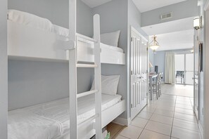 A room with bunk beds, a desk, and a chair, with a view to the outside. - Sunny oceanfront condo w/ two shared pools, hot tub - walk to the beach (Panama City Beach)