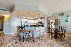 A modern kitchen with a central island, bar stools, and pendant lighting. - Beach-view, high-rise condo with pool - central location (Panama City Beach)