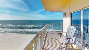 A balcony with a view of the ocean, a wooden deck, and a chair. - Beach-view, high-rise condo with pool - central location (Panama City Beach)