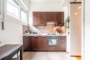 A modern kitchen with dark wooden cabinets, a stainless steel range hood, and a built-in oven. - Carrobbio's Nest - Elegant with Wifi and A/C (Milano)
