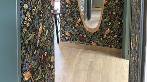 A hallway with a floral wallpaper, a mirror, and a sign that reads "LA VIE EST BELLE EN FAMILLE". - The "Mesa Normande": between City and Beach with private garden! (Vaux-sur-Seulles)