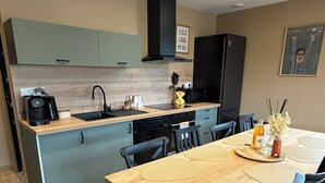 A modern kitchen with a central island, a dining table with chairs, and a microwave. - The "Mesa Normande": between City and Beach with private garden! (Vaux-sur-Seulles)