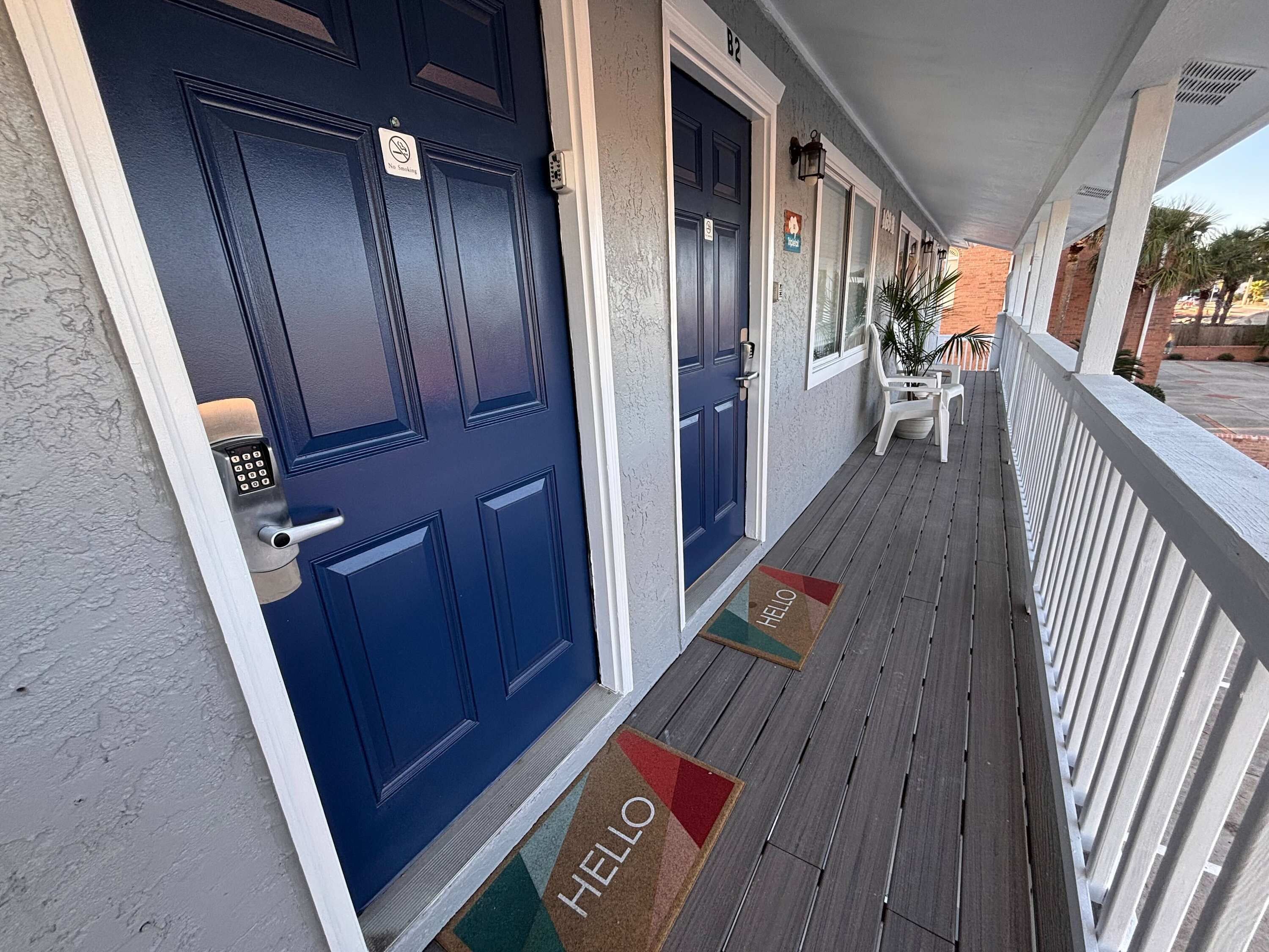 A hotel entrance with a blue door, a keypad lock, and a 'No Smoking' sign.