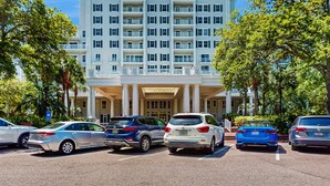 A multi-story hotel with a grand entrance, parking lot, and surrounding greenery. - 3rd-floor Condo with pools, marina, tennis, large balcony, beach access (Miramar Beach)