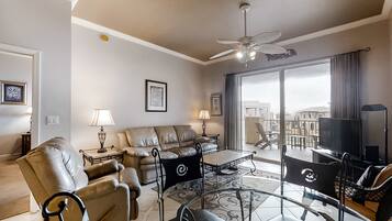 A modern living room with leather sofas, a glass coffee table, and a TV.