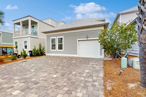 Un quartiere residenziale con una casa a due piani, un garage e un vialetto asfaltato.