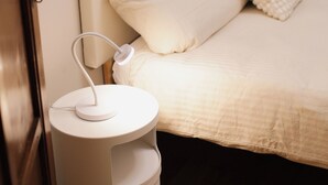 Un dormitorio con cama, una mesita de noche con lámpara y suelo de madera.