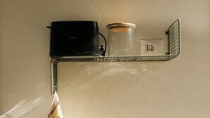 Una cocina con una toalla colgada, una cafetera y un frasco en un estante.