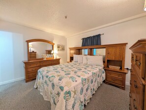 Un dormitorio con una cama grande, cómoda de madera y un espejo.
