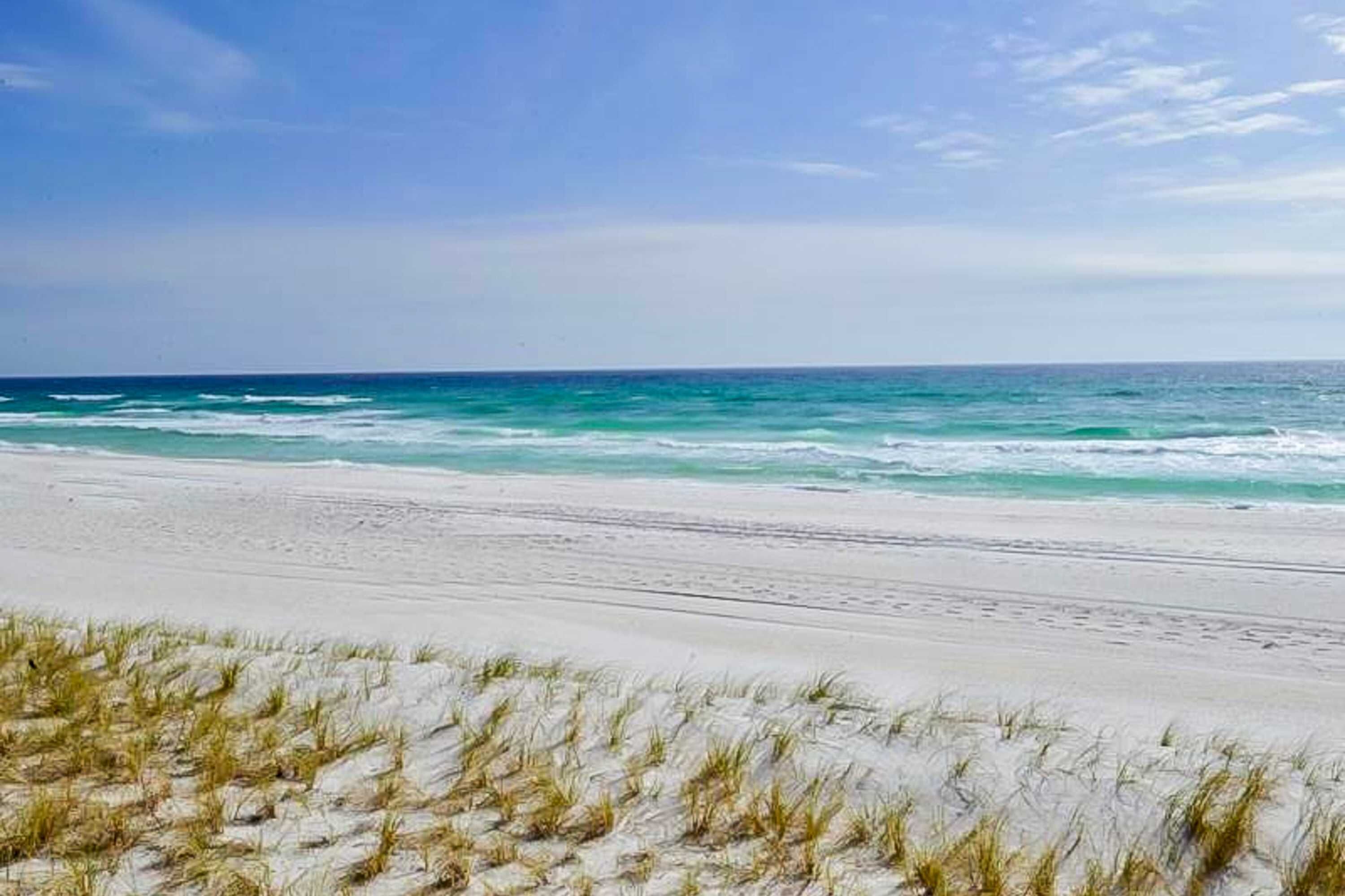 A beach with white sand and ocean waves.