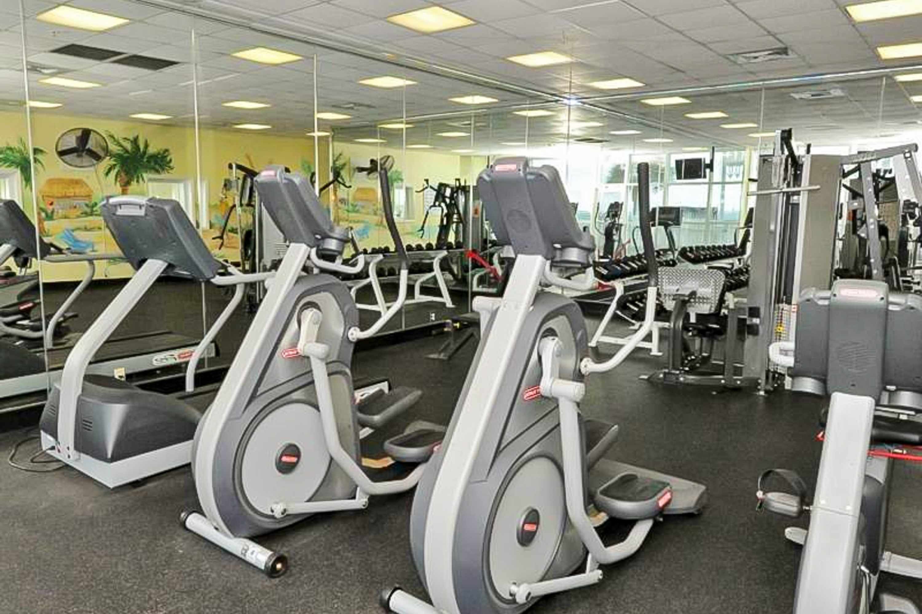 Un gimnasio con cintas de correr, máquinas de pesas y un espejo grande.