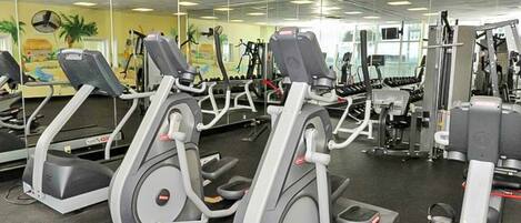 Un gimnasio con cintas de correr, máquinas de pesas y un espejo grande.