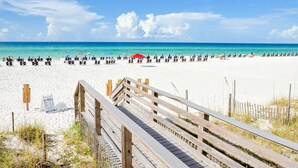 A beach with a wooden boardwalk leading to the sand, a clear blue sky, and the ocean in the background. - Gulf-front condo with balcony, ocean view, W&D, pool, hot tub & tennis (Miramar Beach)