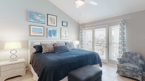 Un dormitorio con cama, mesita de noche, silla y una obra de arte en la pared.