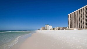 A beach with a hotel in the background.