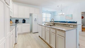 Una cocina moderna con armarios blancos, encimera de granito y lavavajillas integrado.