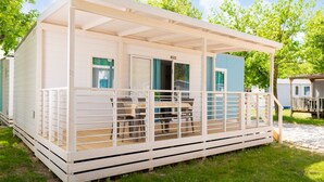 Une maison mobile dotée d’un porche abrité, d’une table à manger et de chaises.