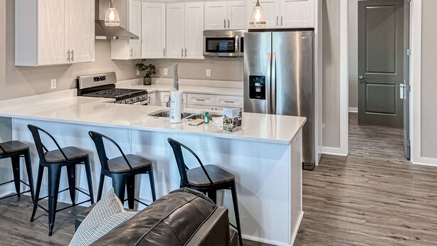 A modern kitchen with white cabinets, stainless steel appliances, a central island with bar stools, and pendant lighting. - Dog-friendly abode with a washer/dryer, central AC, & patio - perfect central location (Port St. Joe)