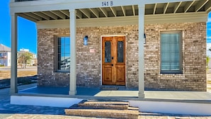 A two-story building with a brick facade, a wooden double door, and a balcony. - Dog-friendly abode with a washer/dryer, central AC, & patio - perfect central location (Port St. Joe)