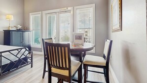A dining area with a round table, two chairs, a lamp, and a cabinet. - Spacious condo with large living area, private balcony & shared pool (Santa Rosa Beach)