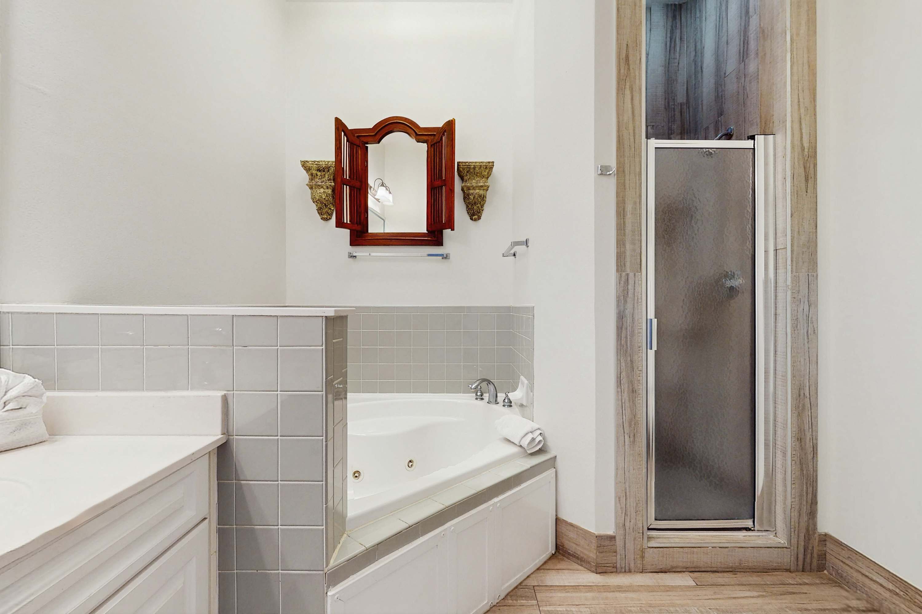 A bathroom with a bathtub, a shower, and a vanity with a mirror.