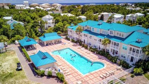 Ein Resort mit einem großen Schwimmbecken, mehreren Gebäuden mit blauen Dächern und üppiger Bepflanzung.