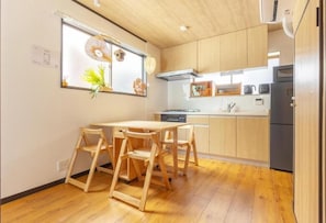 Una cocina compacta con armarios de madera, una mesa de comedor con sillas y una ventana con adornos.