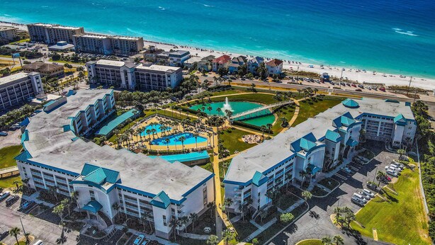 An aerial view of a resort with multiple buildings, a central pool area, and a beach. - Big 'O Beach Miramar/Destin (Miramar Beach)
