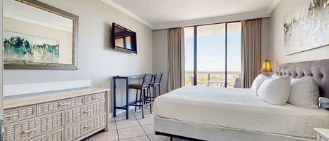 A hotel room with a bed, a desk, a chair, a TV, and a large window.