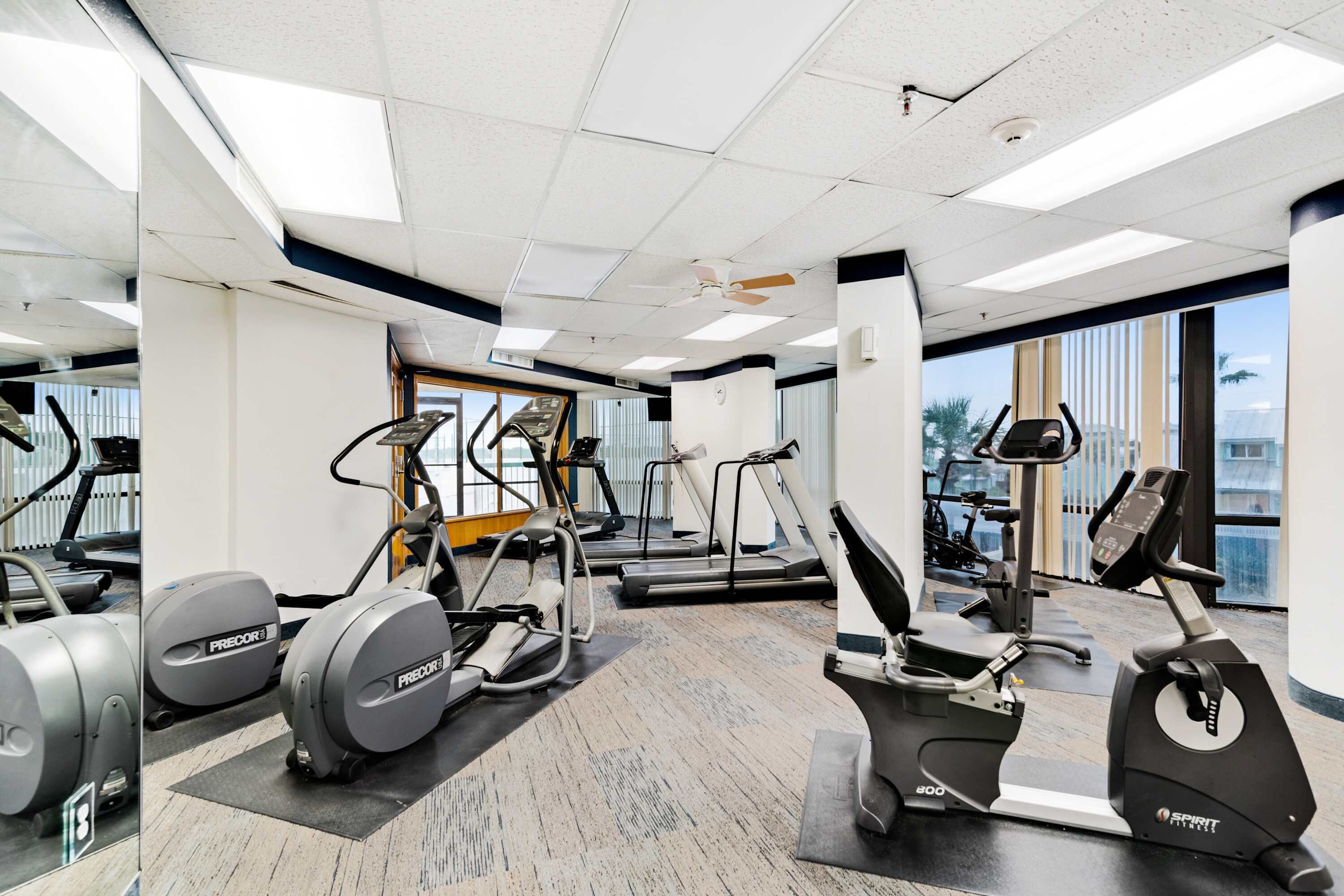 Une salle de sport équipée de tapis de course, d’appareils elliptiques et de vélos d’appartement.