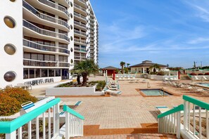 A hotel with multiple balconies, a pool area with sun loungers, and a staircase with a turquoise railing. - Gulf-view resort condo with pool, hot tubs, & over-street beach access (Miramar Beach)
