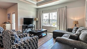 A living room with a TV, two sofas, a coffee table, and a window with curtains.