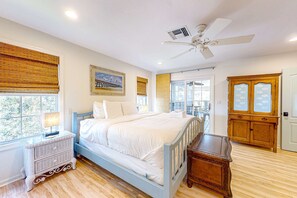 A bedroom with a bed, nightstand, wooden cabinet, and a ceiling fan. - Beautiful dog-friendly home with screened porch & pool access in great location (Cape San Blas)