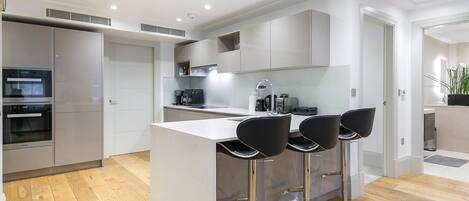 Een moderne keuken met een centraal eiland, barkrukken en inbouwapparatuur.