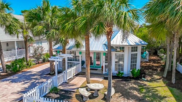 Un resort con un patio cercado, palmeras y una estructura tipo pabellón con techo azul.