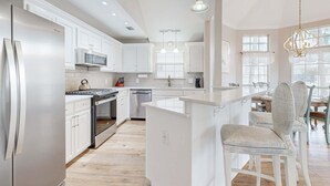 Una cocina moderna con armarios blancos, electrodomésticos de acero inoxidable y una isla central.