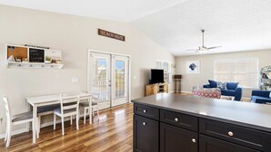 A kitchen with a central island, white dining table with chairs, and a sign reading "BEACH HOUSE". - Dog-friendly coastal getaway with private pool, patio, & grill (Port St. Joe)
