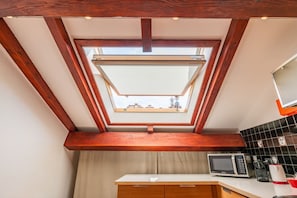 A kitchen with a skylight, wooden beams, a microwave, and a sink. - De Amicis' Nest - City Center (Milano)