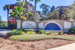 A sign for "Villages Crystal Beach" with a tiled archway and a landscaped garden. - Gorgeous, multi-level home with pool, hot tub & two balconies - dog-friendly (Destin)