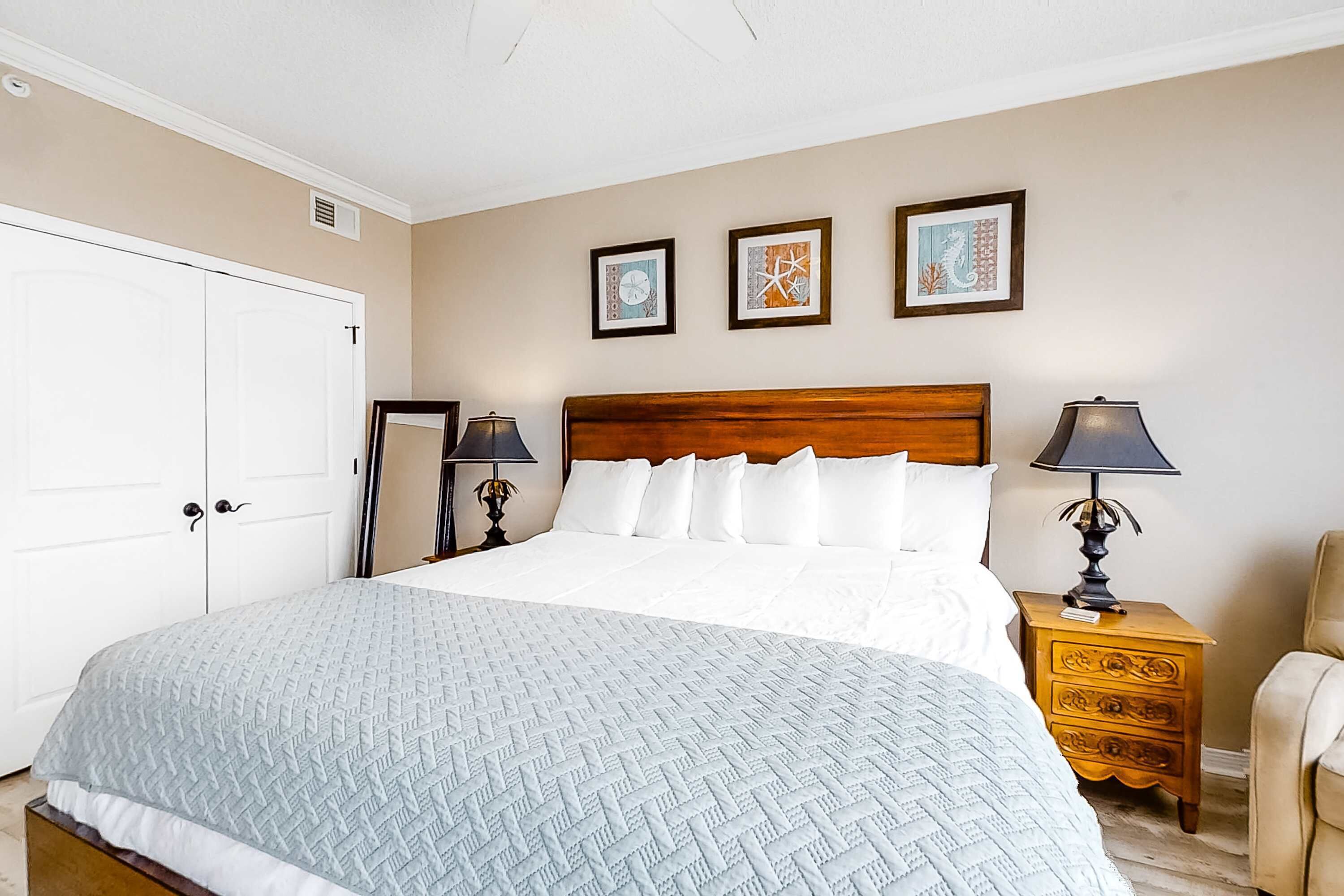 A neatly arranged bedroom with a large bed, two bedside tables with lamps, a chair, and a wardrobe.