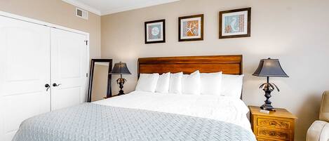A neatly arranged bedroom with a large bed, two bedside tables with lamps, a chair, and a wardrobe.
