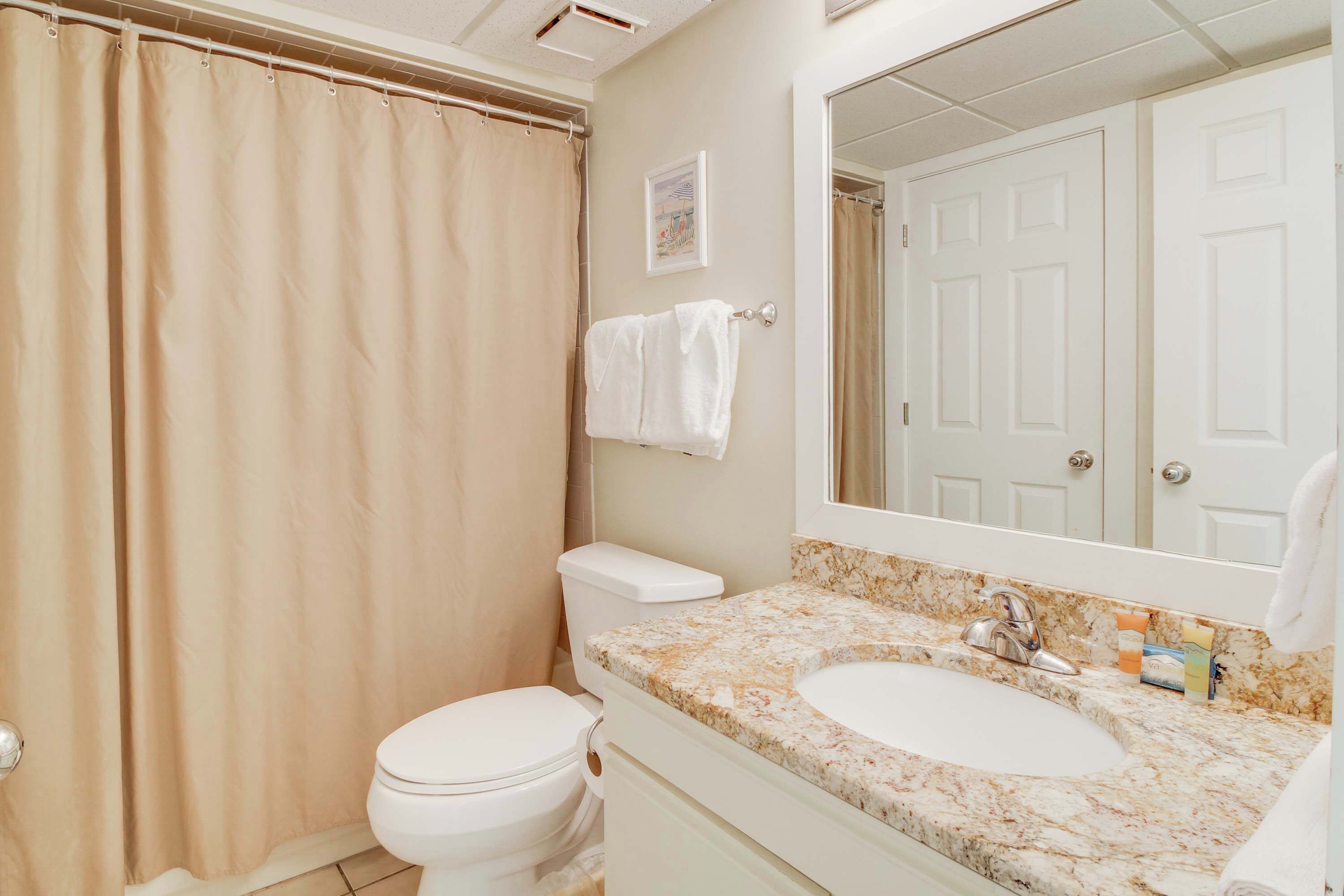A bathroom with a toilet, sink, and shower curtain.