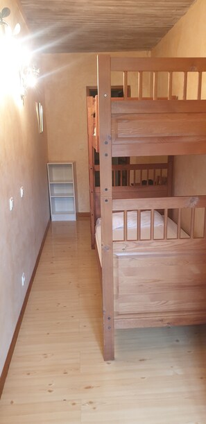 A bunk bed with a wooden frame, a white shelf unit, and a wooden floor. - Quiet 4-person vacation rental in the countryside, with amenities just a 5-minute walk away, a pool, and more (Maubec)